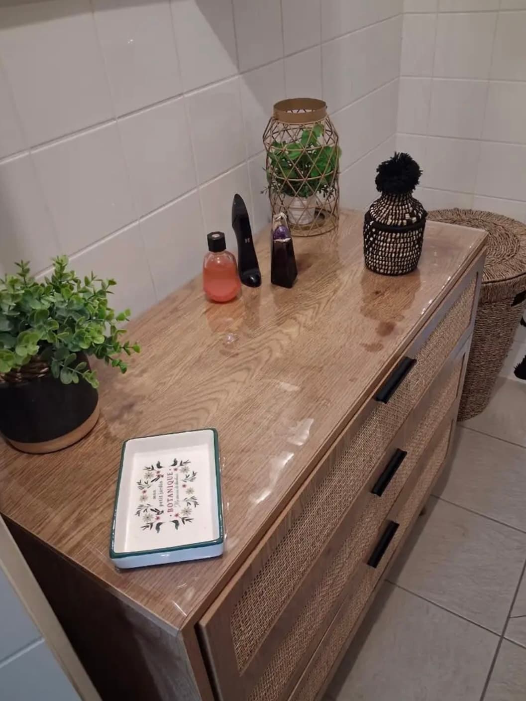 Commode van hout en rotan — op het blad de mat, ernaast zeep, een lantaarn en een bloempot