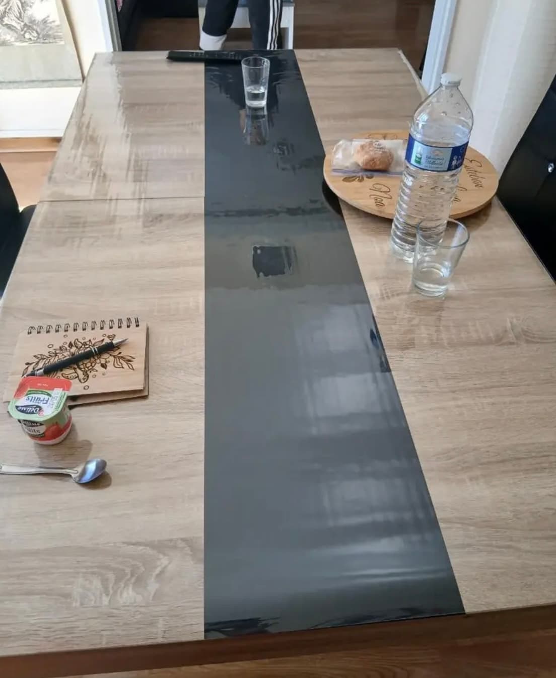 Ontbijt op een lange tafel met grafietgrijze strook: water, glazen, notitieboek — alles op de mat