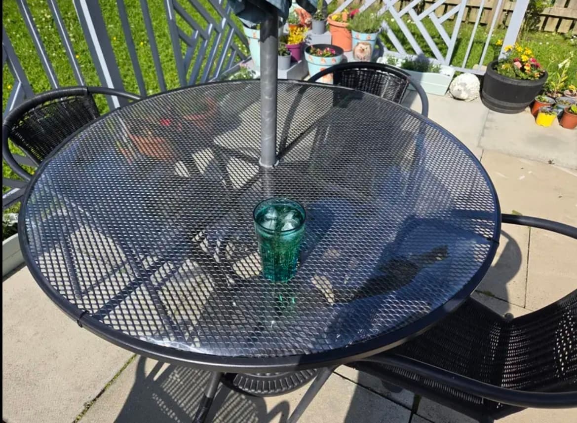 Mat op een ronde tafel op het terras, een glas drinken in het midden, rondom bloempotten