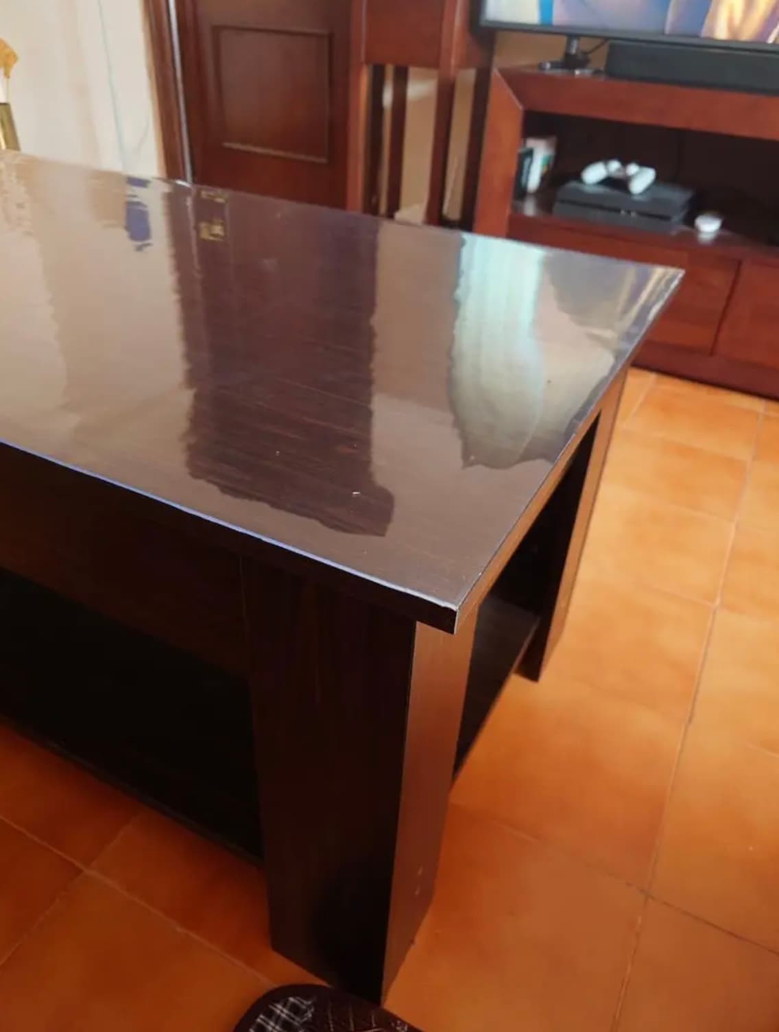 Donkere wengé console in de woonkamer, het blad onder een transparante mat, op de vloer terracotta